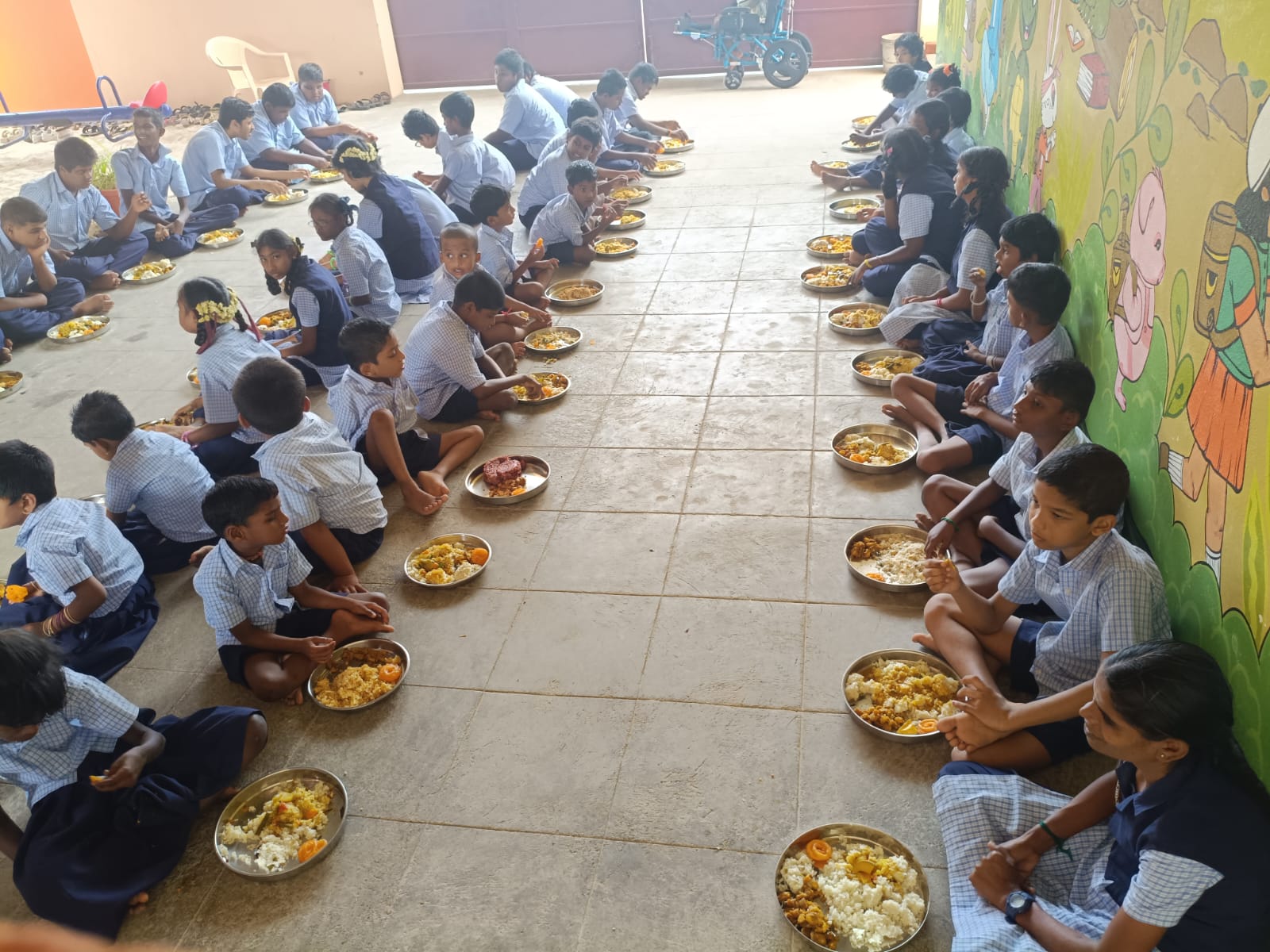 Differently abled children seated in rows eating a meal provided by the trust