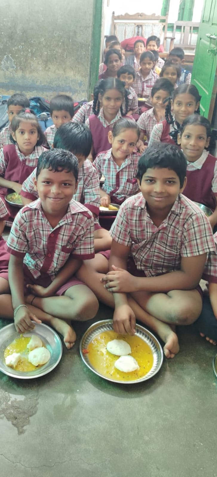 Smiling schoolchildren in uniform with plates of a free breakfast served by the trust