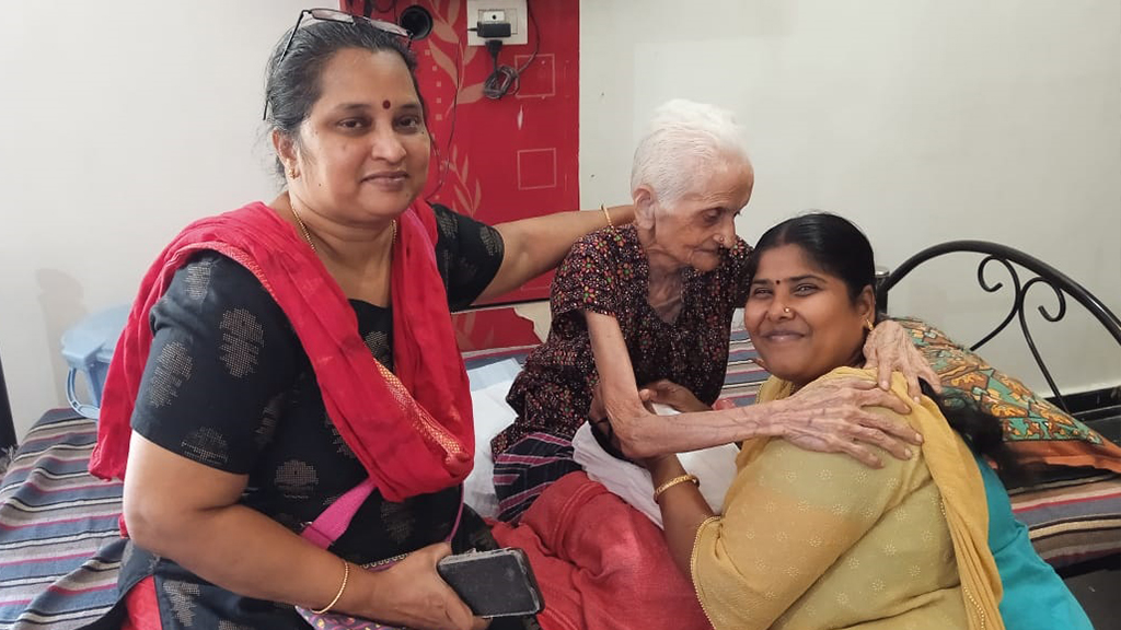 Two trust volunteers warmly embracing an elderly resident at a care home