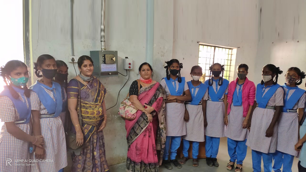 Schoolgirls beside a newly installed sanitary pad vending and incinerator unit